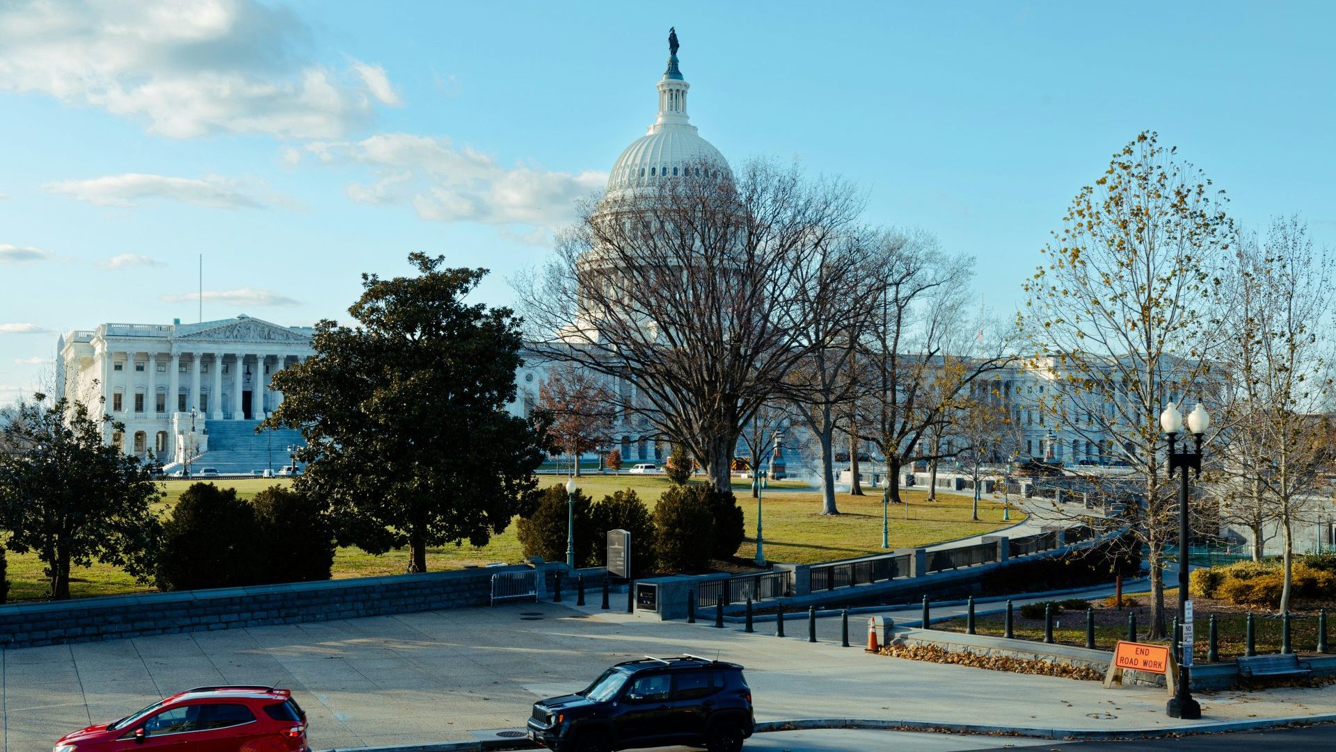 two cars parked in a parking lot in front of the capitol building