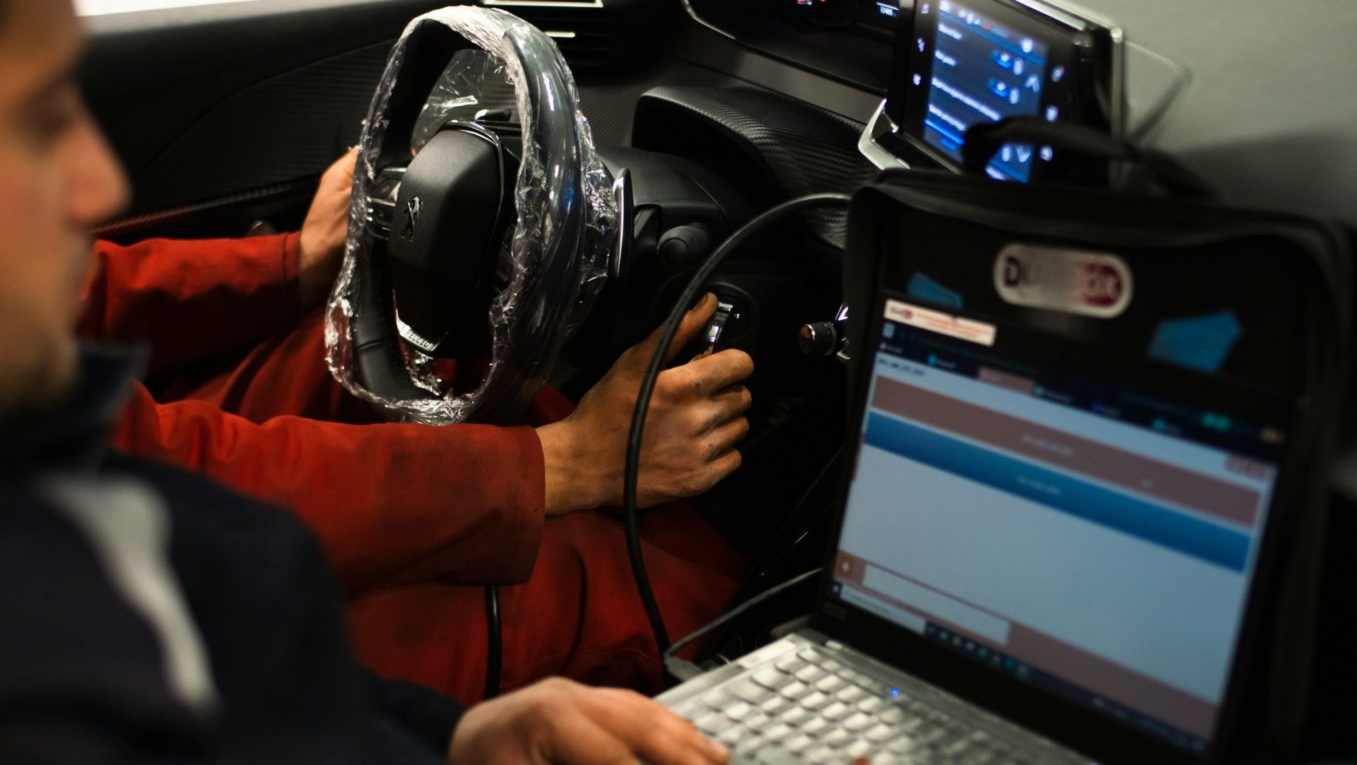 A man sitting in a car using a laptop computer